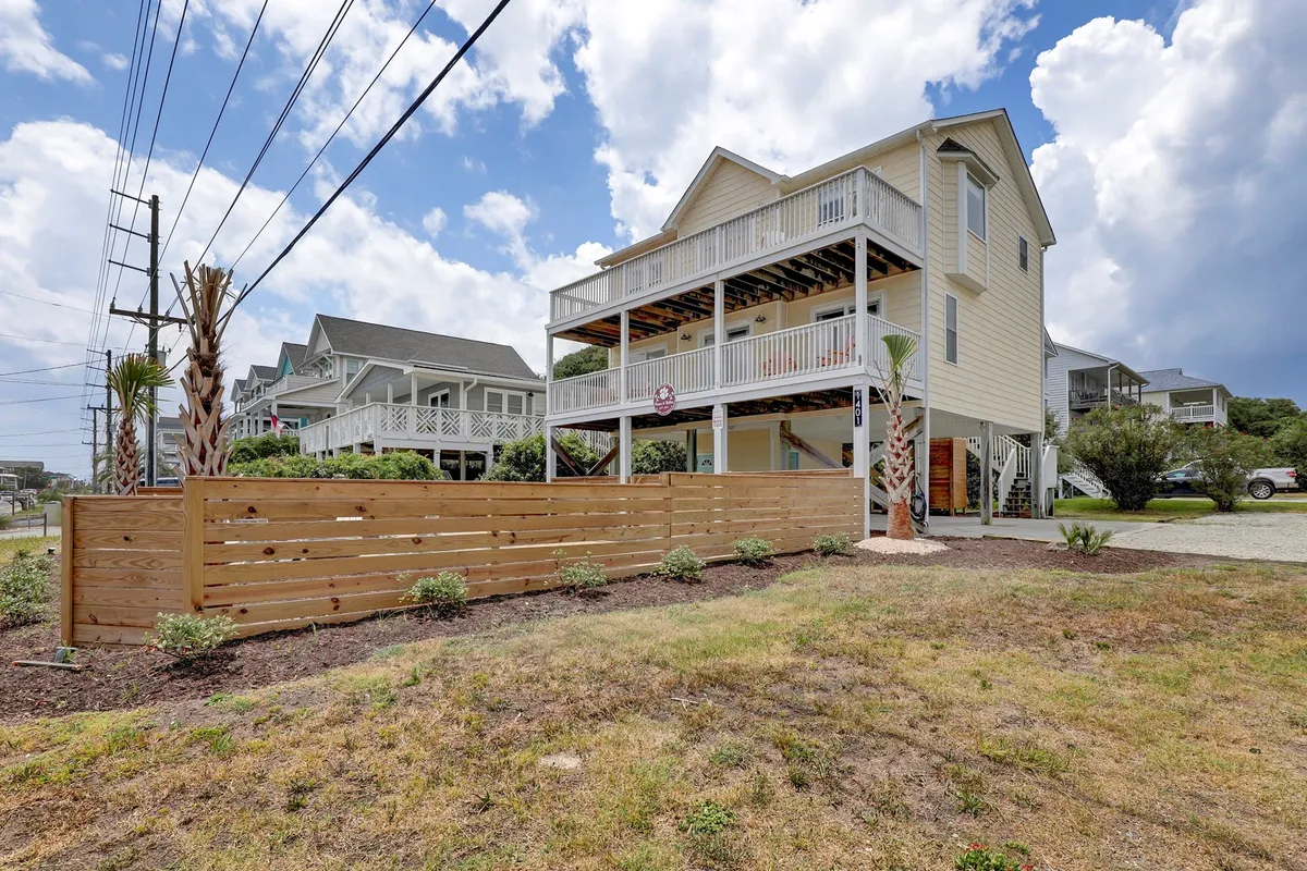 A welcoming shot of the house's exterior, featuring the wooden fence, palm trees, and the home itself. The fenced yard is clearly visible, providing a safe and inviting space for children and pets to enjoy outdoor play.