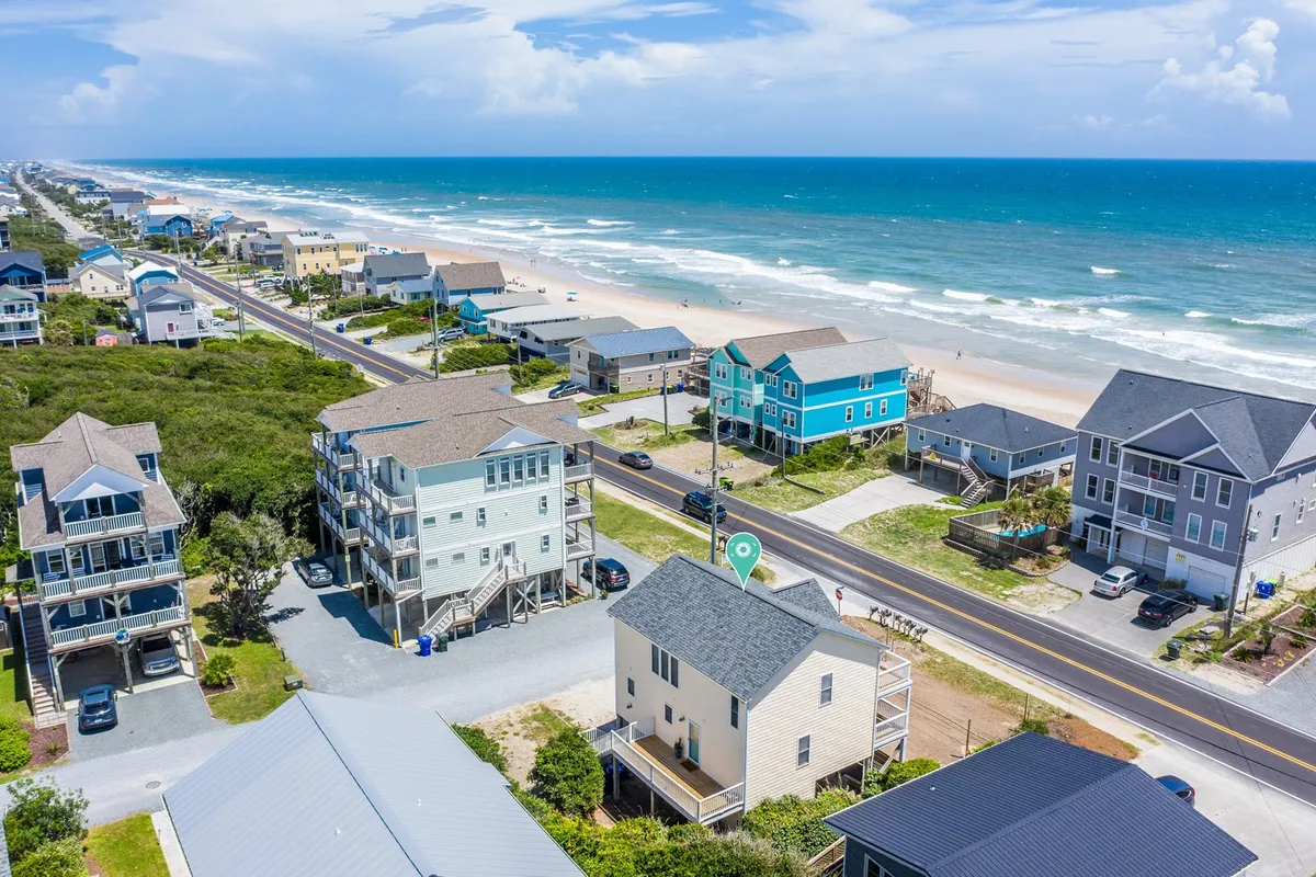 A panoramic coastal view showcasing oceanfront properties, colorful houses, and a coastal road, inviting feelings of exploration and accessibility. The coastline and visible trails suggest walks, beach outings, and scenic exploration.